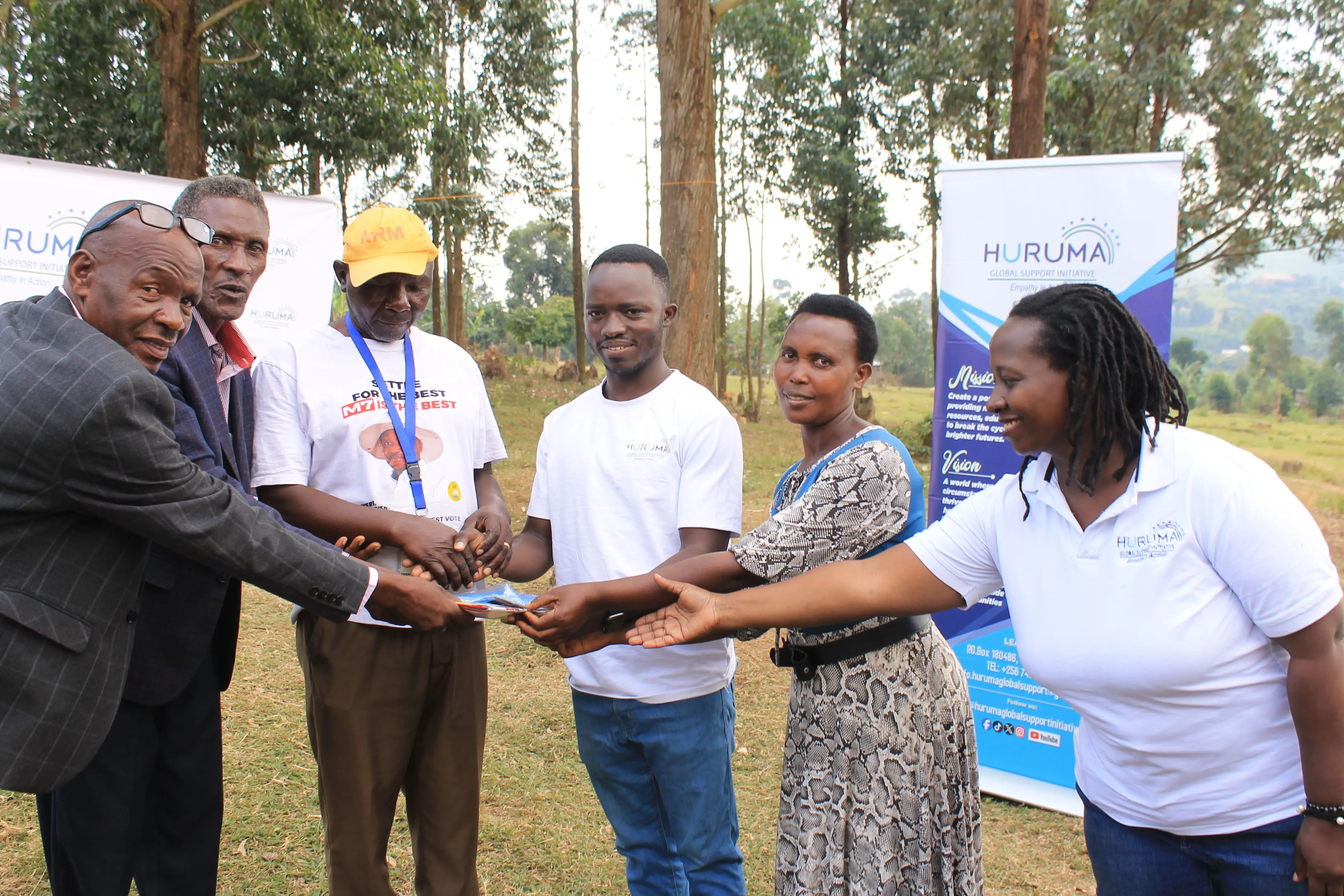 A Huruma team member handing over learning materials with a handshake