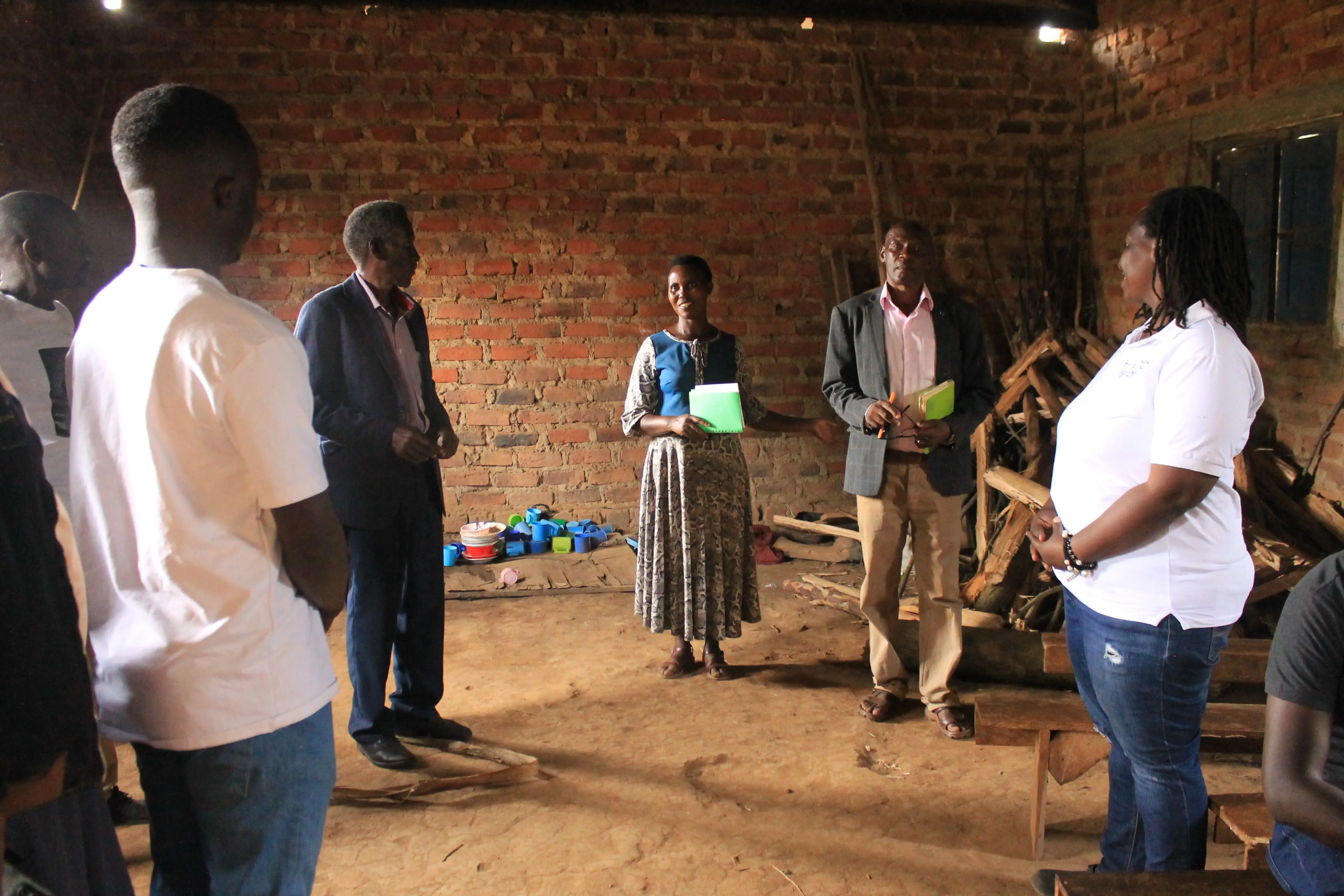 Huruma team members talking with school staff inside a bare brick classroom